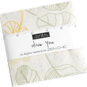 May include: A white fabric square with a green and yellow leaf pattern. The fabric has a stitched edge and a label that reads "olive you by Brigitte Heitland for ZEN CHIC".