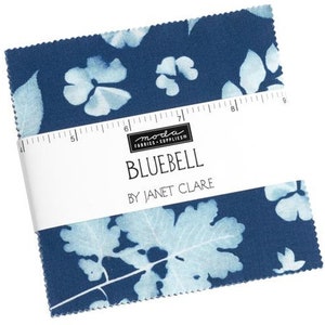 May include: A blue fabric square with a white floral pattern. The fabric is labeled "Bluebell by Janet Clare" and "Moda Fabrics & Supplies".