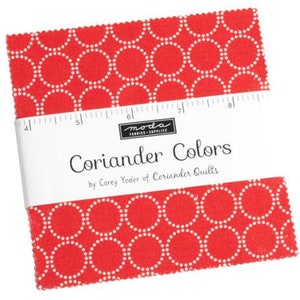 May include: A red fabric square with a white polka dot pattern of circles. The fabric is labeled "Coriander Colors" by Corey Yoder of Coriander Quilts.
