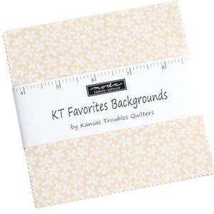 May include: A stack of fabric squares with a cream-colored floral pattern. A white band with the text "KT Favorites Backgrounds" wraps around the fabric. The brand "moda fabrics supplies" is also visible.