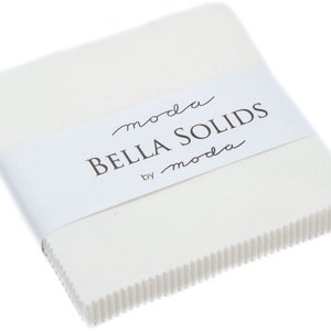 May include: A stack of square white fabric pieces secured with a white paper band. The band features the text moda BELLA SOLIDS by moda in black lettering. The fabric edges are pinked with a zigzag pattern, creating a textured appearance.
