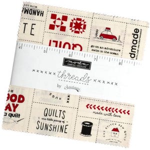 May include: A beige fabric square with red and black text and images. The text includes "handmade with love", "quilts are little pieces of sunshine", and "go on an adventure swim in the ocean".