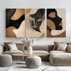 Puede incluir: Tres impresiones de arte abstracto con un retrato estilizado en negro y marrón de una mujer con los ojos cerrados. Las impresiones están enmarcadas y colgadas en una pared blanca sobre un sofá beige.