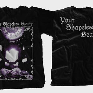 May include: Black t-shirt with the text "Your Shapeless Beauty" on the front and back. The front design features a framed image with a clock, candles, and a figure. The back of the shirt has the text in a gothic font.