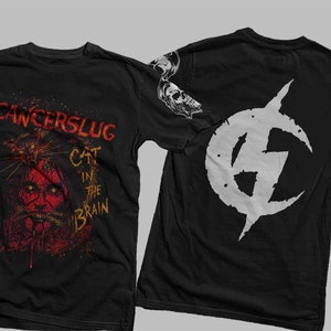 Puede incluir: Camiseta negra con un gráfico de calavera blanca en la manga y un gráfico de un gato en la cabeza de una persona con el texto "CANCERSLUG CAT IN THE BRAIN". La parte posterior de la camiseta tiene un gráfico blanco de un rayo en un círculo.