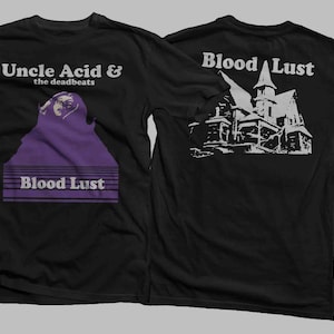 Könnte beinhalten: Schwarzes T-Shirt mit dem Text "Uncle Acid & the deadbeats" und "Blood Lust" mit einer lila Grafik auf der Vorderseite. Die Rückseite des Shirts zeigt eine weiße Illustration eines Spukhauses und die Worte "Blood Lust".