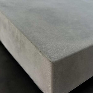 May include: Close-up of a smooth, gray concrete surface. The surface is slightly textured and has a subtle sheen.