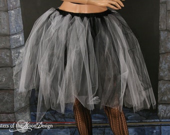 May include: A white tulle skirt with a black waistband. The skirt is layered and has a ruffled hem.