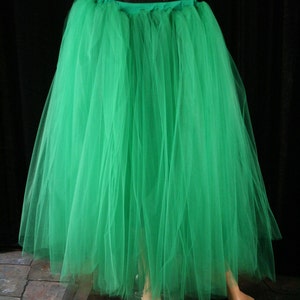 May include: A long, flowing green tulle skirt. The skirt is gathered at the waist and has a slight A-line shape.