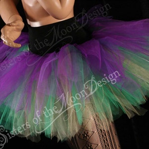 May include: A multi-layered tulle skirt in shades of purple, green, and gold. The skirt is gathered at the waist and has a flowing, voluminous shape.
