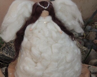 May include: A white felt angel doll with long brown hair, wearing a white dress and a crown with a small white flower. The angel has large white wings.
