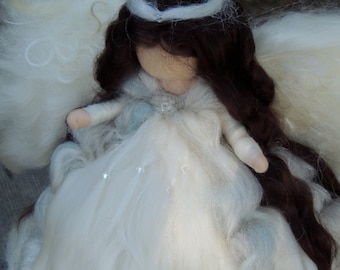 May include: A white felt angel doll with long brown hair and a white halo. The doll is wearing a white dress with blue accents and is holding its hands together in front of its chest.