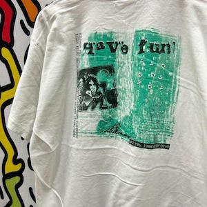 May include: White t-shirt with a green graphic print that says "Have fun!" with a picture of a person and the text "With Hansgrohe".