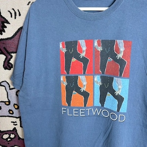 May include: A blue t-shirt with a graphic design. The design features a figure in a suit repeated four times in different coloured squares. The word "FLEETWOOD" is printed in white below the graphic.