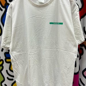 May include: White t-shirt with a green rectangular logo that says "hansgrohe" on it.