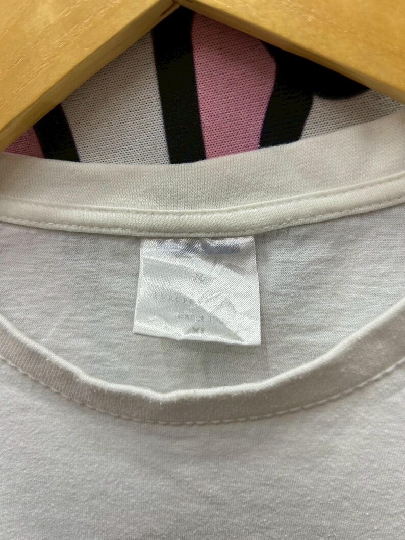 May include: White t-shirt with a white tag that says "EUROSIZE" and "SIZE 170/82" with a size "XL" printed on it.