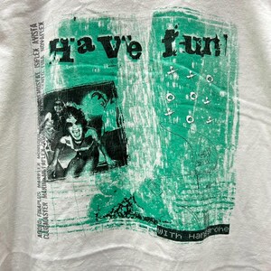 May include: White t-shirt with a green and black graphic print that says "Have fun!" with the text "WITH Hangrohe" at the bottom.