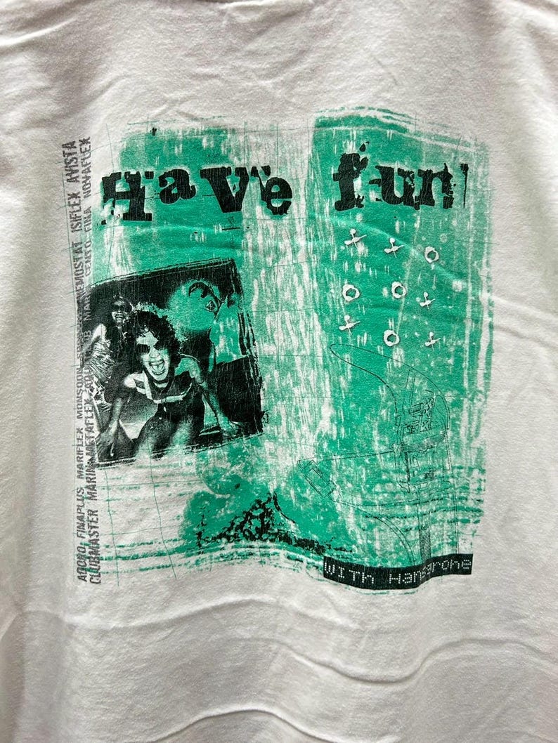 May include: White t-shirt with a green and black graphic print that says "Have fun!" with the text "WITH Hangrohe" at the bottom.