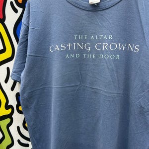 May include: A blue t-shirt with the text "The Altar Casting Crowns And The Door" printed on the front.