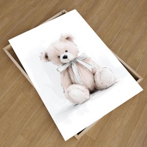 May include: A framed print of a watercolour illustration of a teddy bear. The bear is light pink with a white bow and black eyes. The artwork is set against a white background.