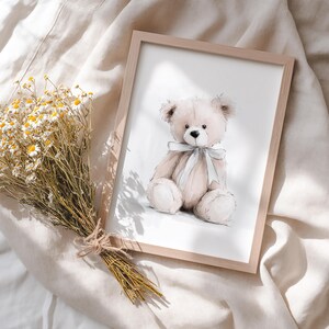 May include: A framed print of a watercolour illustration of a beige teddy bear with a light blue ribbon. The bear is sitting, with a soft, plush appearance. A bouquet of dried yellow and white flowers is tied with twine, adding a natural touch.