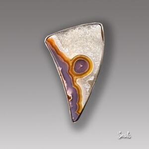 May include: A silver pendant featuring a unique, irregularly shaped agate stone with a purple and orange pattern. The stone is set in a silver bezel and has a white, crystalline background.