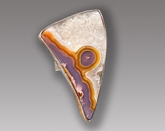 May include: A silver ring with a triangular shaped agate stone. The stone has a white, purple, and orange pattern.