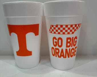 May include: Two white foam cups with orange graphics. One cup features a large orange "T", and the other has a checkered design with the words "GO BIG ORANGE".