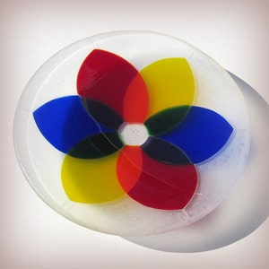 Pu&ograve; includere: Un design floreale in vetro colorato. Il fiore ha sei petali rossi, gialli, blu e verdi, disposti in un motivo circolare. Il fiore &egrave; posto su un piatto rotondo di vetro trasparente. Il design &egrave; vibrante e accattivante.