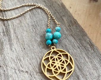May include: Gold-toned necklace featuring a circular pendant with an intricate floral design. The necklace includes a chain and is adorned with turquoise beads. The pendant is suspended from the beads and chain, creating a delicate and stylish accessory.