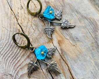 May include: A pair of dangle earrings with a blue glass flower charm and bronze leaves.