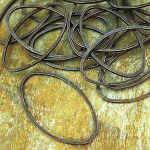 May include: A pile of oval-shaped metal rings, with a rustic, aged bronze finish. The rings are arranged in a random pattern, with some overlapping.