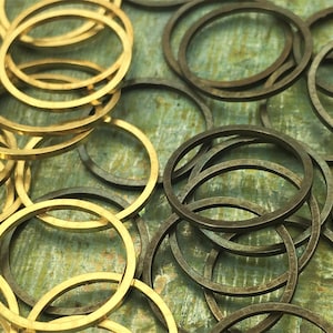 May include: A close-up of two piles of metal rings. One pile is made of gold-coloured rings, and the other pile is made of dark grey rings.
