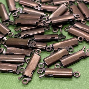 May include: A pile of antique bronze-colored metal clasps with a spring-loaded mechanism. The clasps are designed to be used for jewelry making or other craft projects.