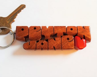 May include: Wooden keychain with the name "Devon Jane" spelled out in individual wooden letters. A small red heart is attached to the end of the keychain.