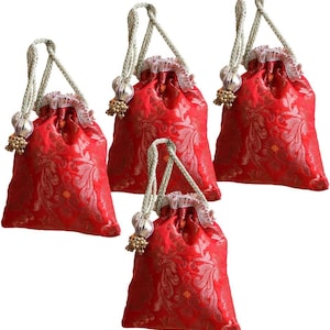 May include: Four red drawstring bags with a floral pattern. Each bag has a silver-colored drawstring with decorative beads and a ruffled trim. The bags are made of a shiny, textured fabric.