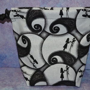 Puede incluir: Una bolsa de cord&oacute;n blanco y negro con un patr&oacute;n repetido de Jack Skellington y Sally de la pel&iacute;cula Pesadilla antes de Navidad.
