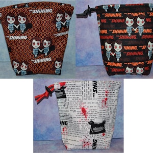 Peut inclure: Trois sacs à cordon avec des thèmes de films d'horreur. Un sac présente un motif répété du mot "SHINING" et un graphisme de deux filles. Un autre sac a le même graphisme et texte sur fond noir. Le troisième sac a un graphisme de machine à écrire et du texte.