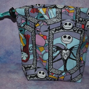 Puede incluir: Una bolsa de cord&oacute;n morado, azul y rosa con un patr&oacute;n repetido de Jack Skellington de Pesadilla antes de Navidad. La bolsa tiene un cord&oacute;n turquesa.