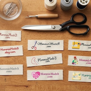 May include: A collection of rectangular fabric labels featuring the text MommieMadeIt.com or MommieMadeIt.etsy.com, accompanied by various sewing-themed illustrations including a pincushion, scissors, a thimble, a heart, and a sewing machine.