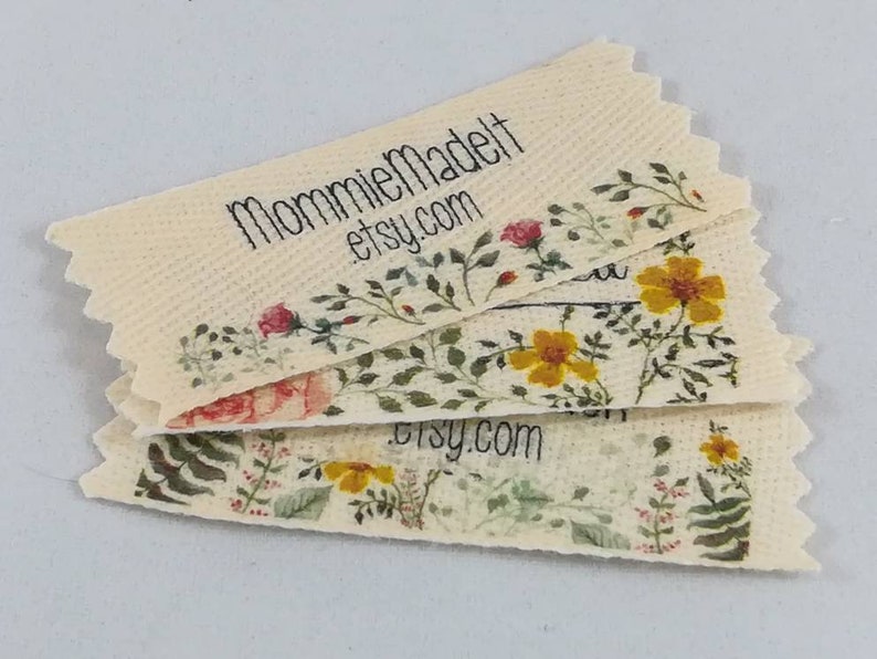 May include: Stack of beige fabric labels with a floral design and the text "MommieMadeIt etsy.com".