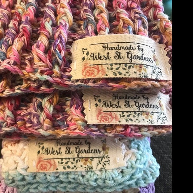 May include: Three handmade crocheted hats with a floral design and a label that reads "Handmade by West St. Gardens".