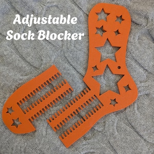 May include: An orange adjustable sock blocker with star cutouts and the text "Adjustable Sock Blocker". The blocker is made of a rigid material and is designed to shape socks during the drying process. The blocker is shown in two pieces.