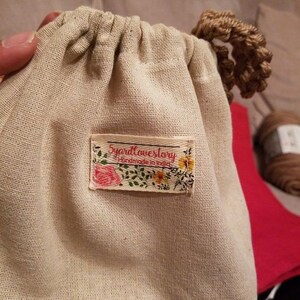 May include: A white cotton drawstring bag with a floral patterned label that reads "5yardlovestory Handmade in India".