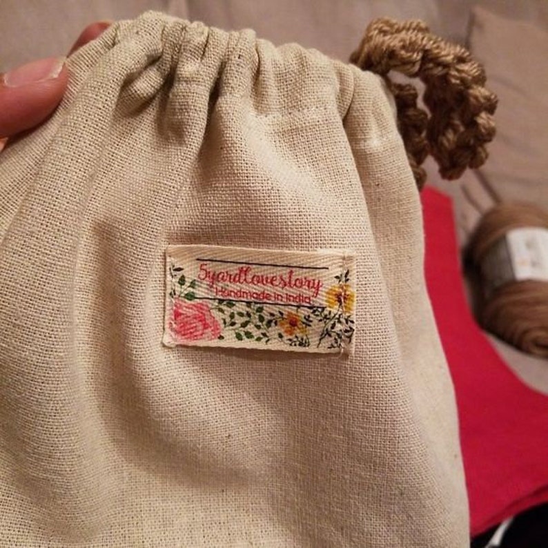 May include: A white cotton drawstring bag with a floral patterned label that reads "5yardlovestory Handmade in India".