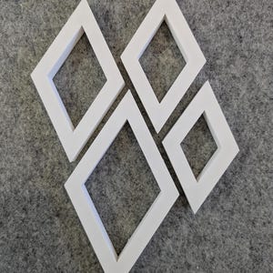 May include: Three white diamond-shaped frames with open centres. The frames are arranged in a cluster, with one large frame positioned at the bottom left, a medium frame at the top left, and a smaller frame on the right side of the group.