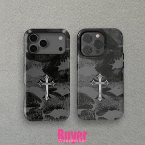Pode incluir: Duas capas de telefone com fundo cinza escuro com um padrão de marcas de batom preto. Cada capa tem uma cruz prateada no centro. As capas são para um smartphone.
