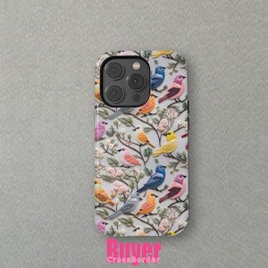 May include: A white iPhone case featuring a colourful bird pattern. The birds are in various shades of blue, yellow, pink, and green. The case has a cutout for the camera lens.
