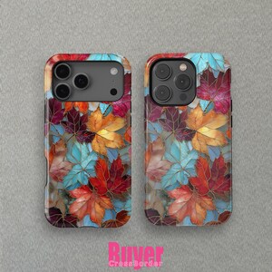 May include: Two phone cases with a colorful autumn leaf design. The cases feature a pattern of red, orange, yellow, and blue leaves with gold outlines. The cases have a glossy finish and a camera cutout.