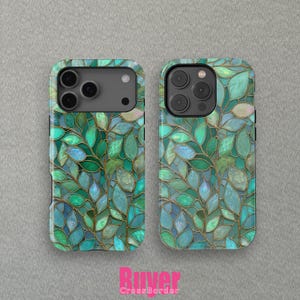 Peut inclure: Deux coques de téléphone avec un motif de feuilles en vitrail. Les coques présentent un motif de feuilles vertes et bleues avec des contours dorés. Les coques sont présentées sur un fond gris.